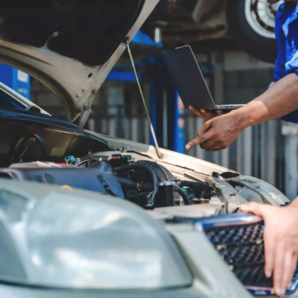 Technician consulting manufacturer repair procedures while inspecting a vehicle.