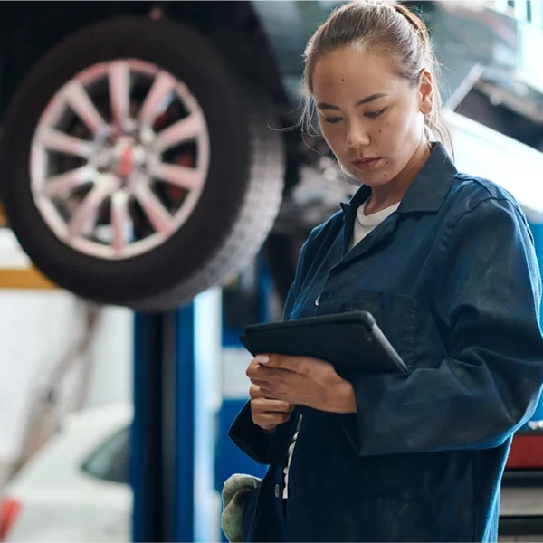 A body shop technician uses a tablet to conduct ADAS calibration after collision repair.