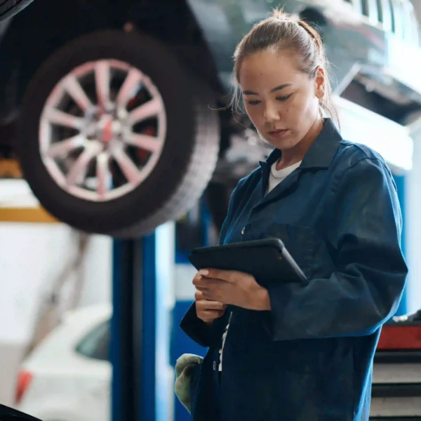 A body shop technician uses a tablet to conduct ADAS calibration after collision repair.